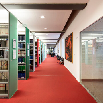 Langer Gang entlang von Bücherregalreihen im Bibliotheksbereich Schloss Ehrenhof.