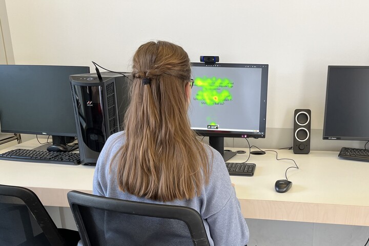 Eine Person sitzt an der Eye-Tracking-Station im ExpLAB im Bibliotheksbereich Schloss Schneckenhof. Auf dem Monitor werden die Augenbewegungen grün dargestellt.