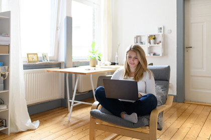 Studentin-Laptop Studentin mit blonden Haaren sitzt zu Hause am Laptop