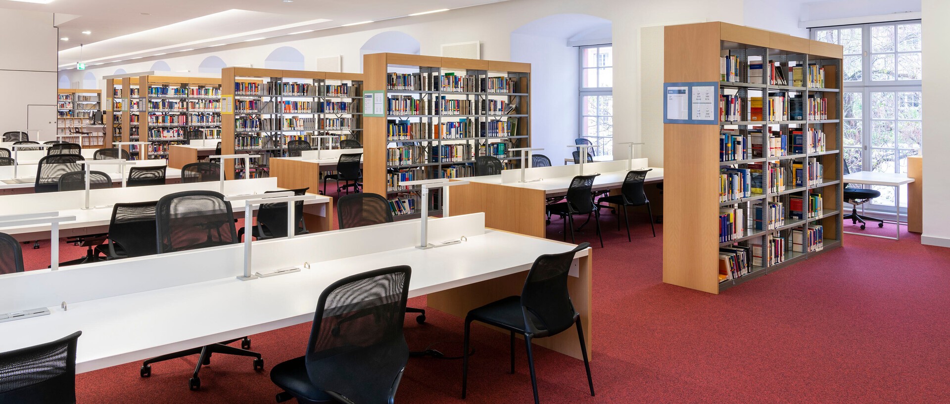 Bücherregalreihen und Arbeitsplätze im Bibliotheksbereich Schloss Schneckenhof.