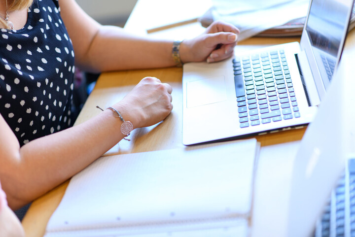 Frau, die am Bildschirm arbeitet. Ausschnitt zeigt Hände und Tastatur