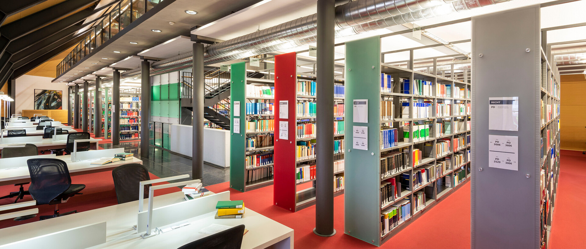 Dachgeschoss im Bibliotheksbereich Schloss Ehrenhof mit Schreibtischarbeitsplätzen und Bücherregalreihen.