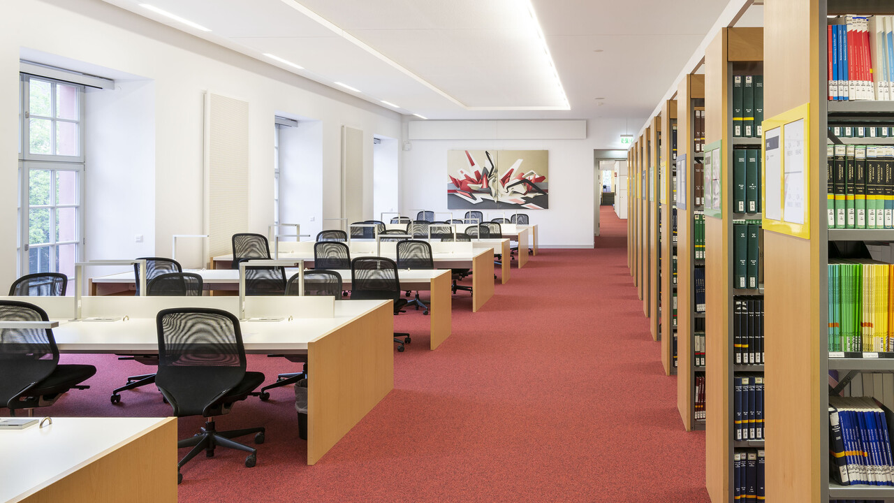 Bücherregalreihen und Arbeitsplätze im Bibliotheksbereich Schloss Schneckenhof.